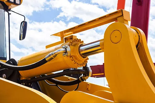 A yellow machine undergoing hydraulic cylinder repairs